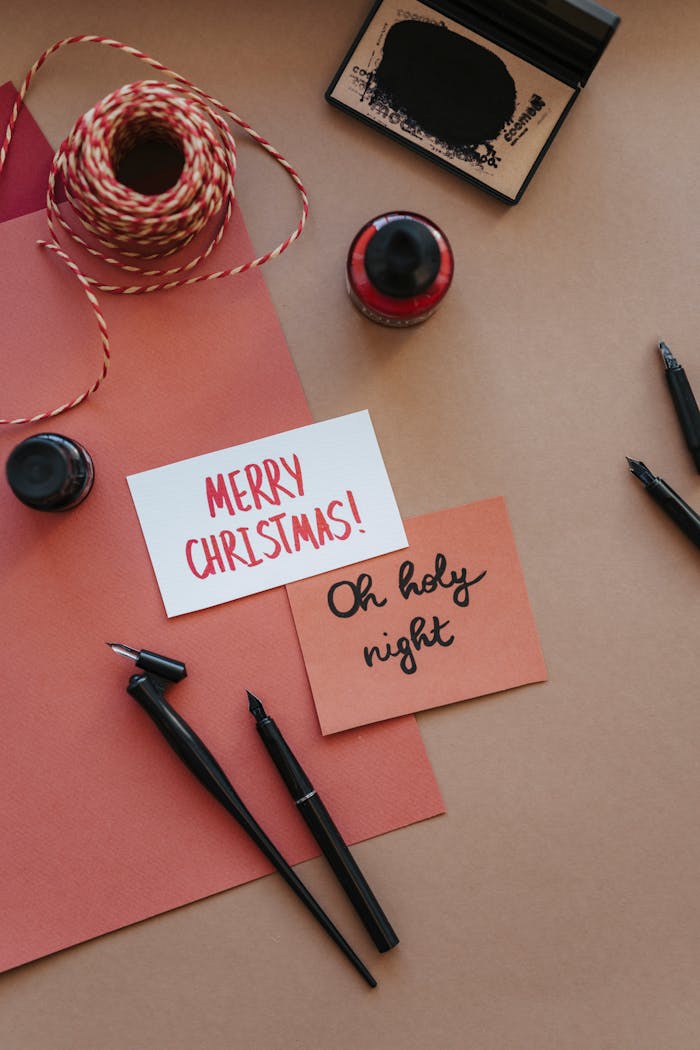 Elegant flatlay with Christmas card calligraphy and writing tools. Perfect for holiday greetings.